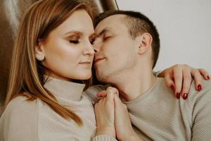 Close-up portrait of a beautiful young kissing couple in bed at home photo