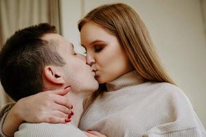 Close-up portrait of a beautiful young kissing couple in bed at home photo