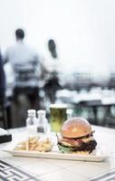 Cheese and bacon gourmet beef burger with french fries and draft beer on a restaurant table photo