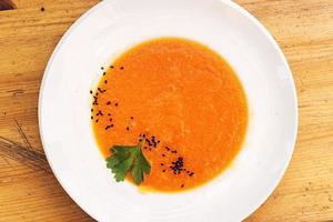 Sopa de calabaza y zanahoria fresca vegetariana orgánica con semillas de sésamo foto