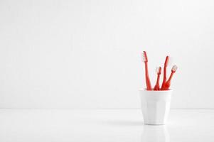 Grupo de cepillo de dientes rojo en un vaso de plástico, cepillo de dientes en el baño. foto