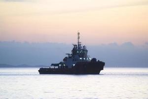 The sunset sky background with vessels silhouette mooring at the sea photo