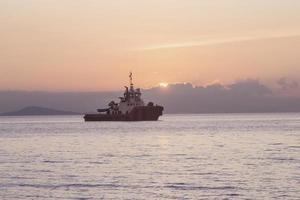 The sunset sky background with vessels silhouette mooring at the sea photo