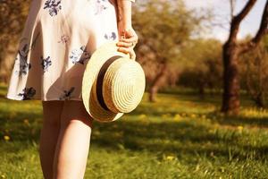 Close-up photo - girl in a straw hat holding a hat in her hands