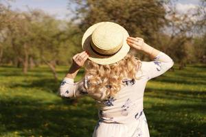 Girl in a straw hat. Back view. Trendy casual summer or spring outfit photo