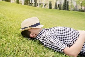 joven pensativo sentado en la hierba en el parque foto