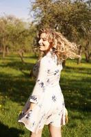 Happy young woman with blonde hair, wearing a dress, posing outdoors photo