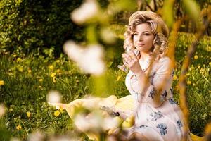 Beautiful young woman with blonde hair in straw hat drinks wine photo