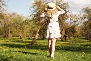 Girl in a straw hat. Back view. Trendy casual summer or spring outfit photo