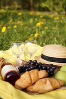 picnic en la hierba con croissant, vino rosado, sombrero de paja, uva