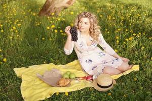 Mujer con uva en un picnic en el jardín de verano foto