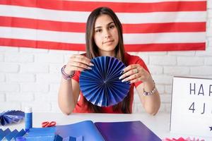 Hermosa mujer haciendo abanicos de papel de bricolaje de colores rojo y azul. foto