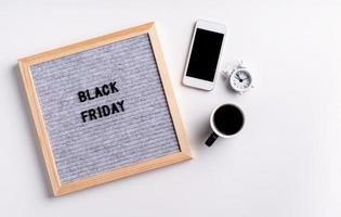 Text black friday on gray, coffee and alarm clock on white background photo