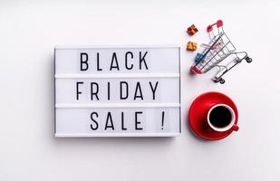 Black Friday Sale words on lightbox with cup of coffee and shopping photo