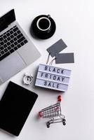 Palabras de venta de viernes negro en caja de luz con taza de café, computadora portátil foto