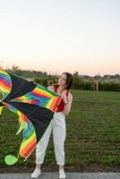 Mujer joven volando una cometa en un parque público al atardecer