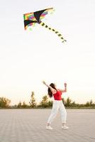 Mujer joven volando una cometa en un parque público al atardecer foto