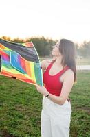 Young woman flying a kite in a public park at sunset