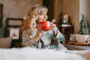 Young woman with cup of tea in Christmas cozy interior