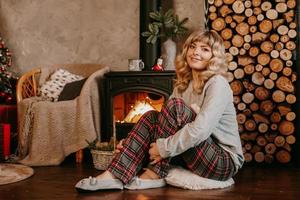 A beautiful young woman in a red plaid sits in New Year interior photo