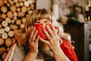 Young woman with cup of tea in Christmas cozy interior