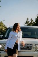 A woman in a white shirt next to a white car on the road photo