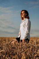 mujer joven feliz con una camisa blanca en un campo de trigo. día soleado.