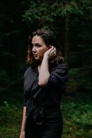 Young woman - close portrait in a dark forest. Woman in black shirt photo