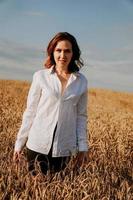 mujer joven feliz con una camisa blanca en un campo de trigo. día soleado. foto