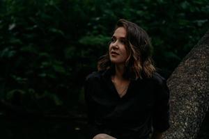 Young woman - close portrait in a dark forest. Woman in black shirt photo