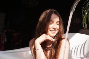 Think positive. Woman waits until the bathtub is filled with water photo