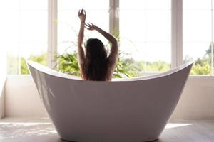 una chica atractiva que se relaja en el baño sobre un fondo claro. foto borrosa