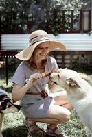 Woman in summer hat grilling meat in the backyard, with her dog photo