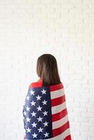 Beautiful young woman with American flag, rear view