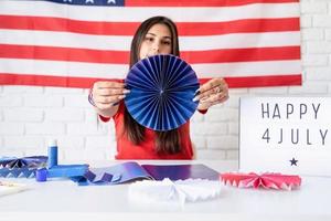 Woman making paper fans of red and blue colors, celebrating photo