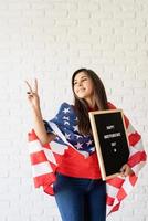 Woman with American flag holding letter board with words Happy 4th July