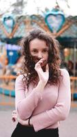 Young hipster woman posing outdoors on the background of carousels photo