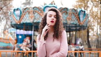 Young hipster woman posing outdoors on the background of carousels photo