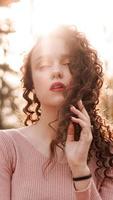 Closeup of a beautiful young woman with a sunset behind her photo