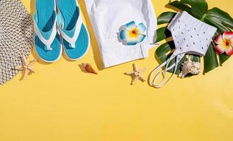accesorios de verano con ropa, zapatos, hojas tropicales y flores. foto