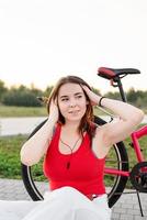 Girl sitting next to her bike listening to the music in the park photo
