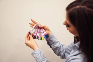 la niña elige el color del esmalte para manicura. probadores de uñas foto