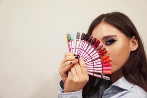 Girl with blue makeup covers her face with a palette with nails photo