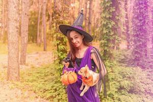 Teenage girl in Halloween costume with a pumpkin and two dogs. photo