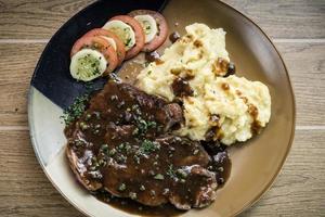 Beef steak meal with mashed potato and gravy sauce on table photo