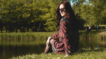 Woman in profile in sunglasses resting on the nature near the river photo