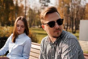 Young couple in quarrel sitting on bench in park photo