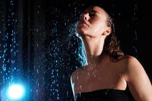 Wet beautiful woman under the falling drops of rain photo