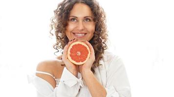 Portrait of pretty middle-aged woman with curly hair with grapefruit