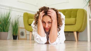 Stress young woman sitting and hold her head on wooden floor
